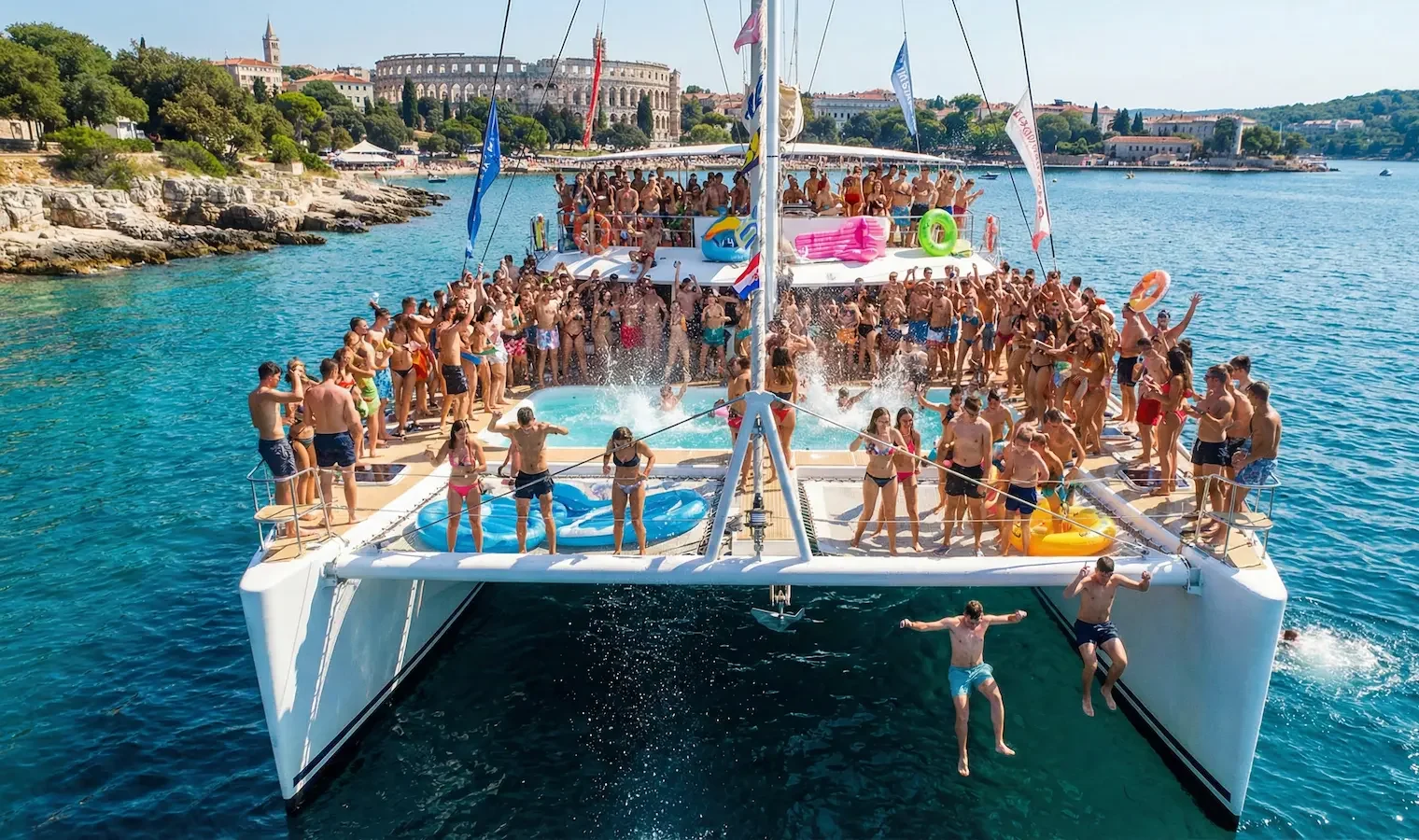 Crowded catamaran party on water.